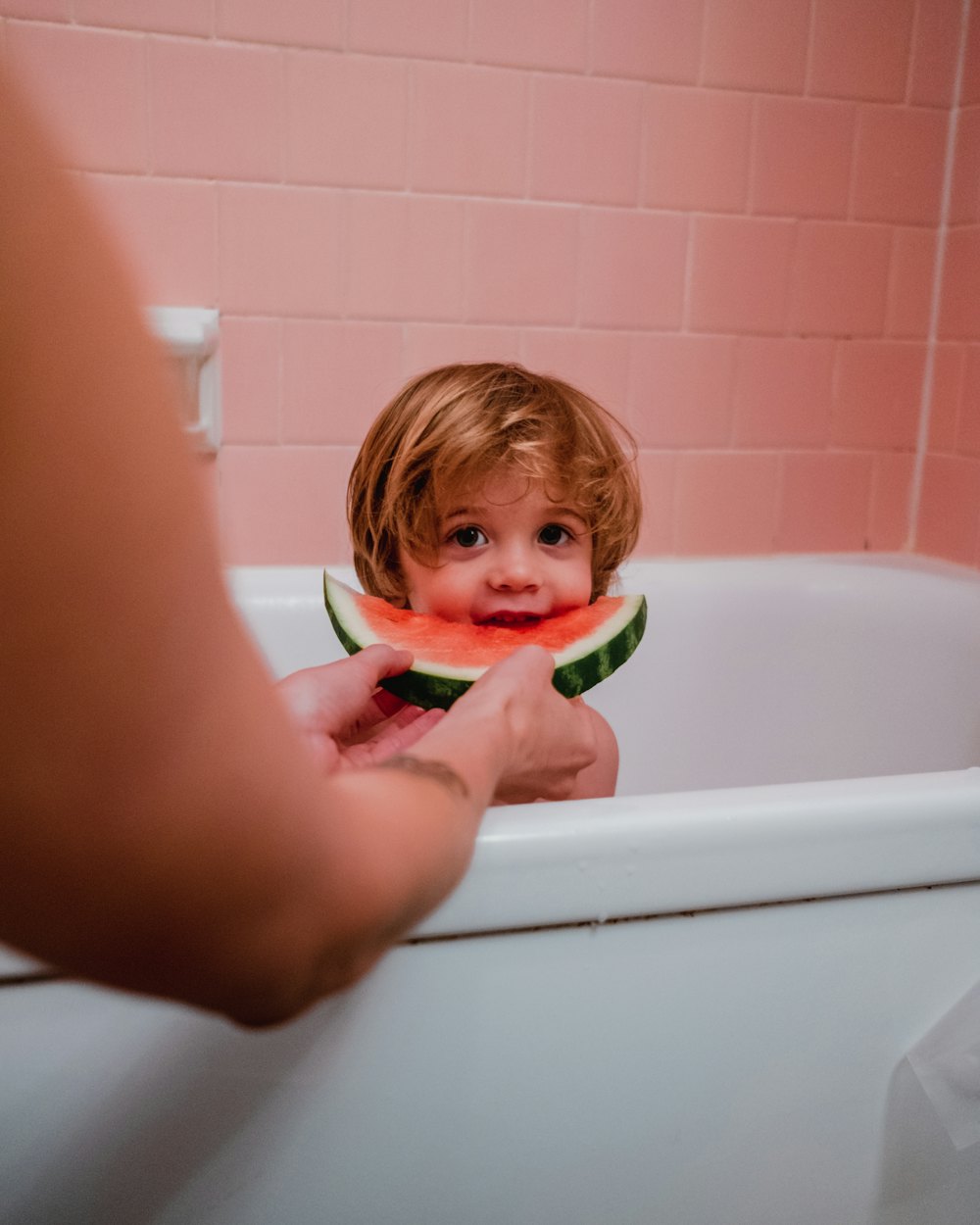 Kleines Kind isst in der Badewanne eine Wassermelone